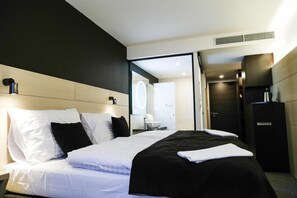 Una habitación de hotel moderna con una cama grande, un escritorio y un baño visible a través de una puerta abierta.