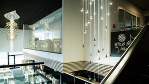 A modern hotel lobby with a glass reception desk, a staircase, and a chandelier. - Hotel Thermal ŠÍRAVA (Kaluža)