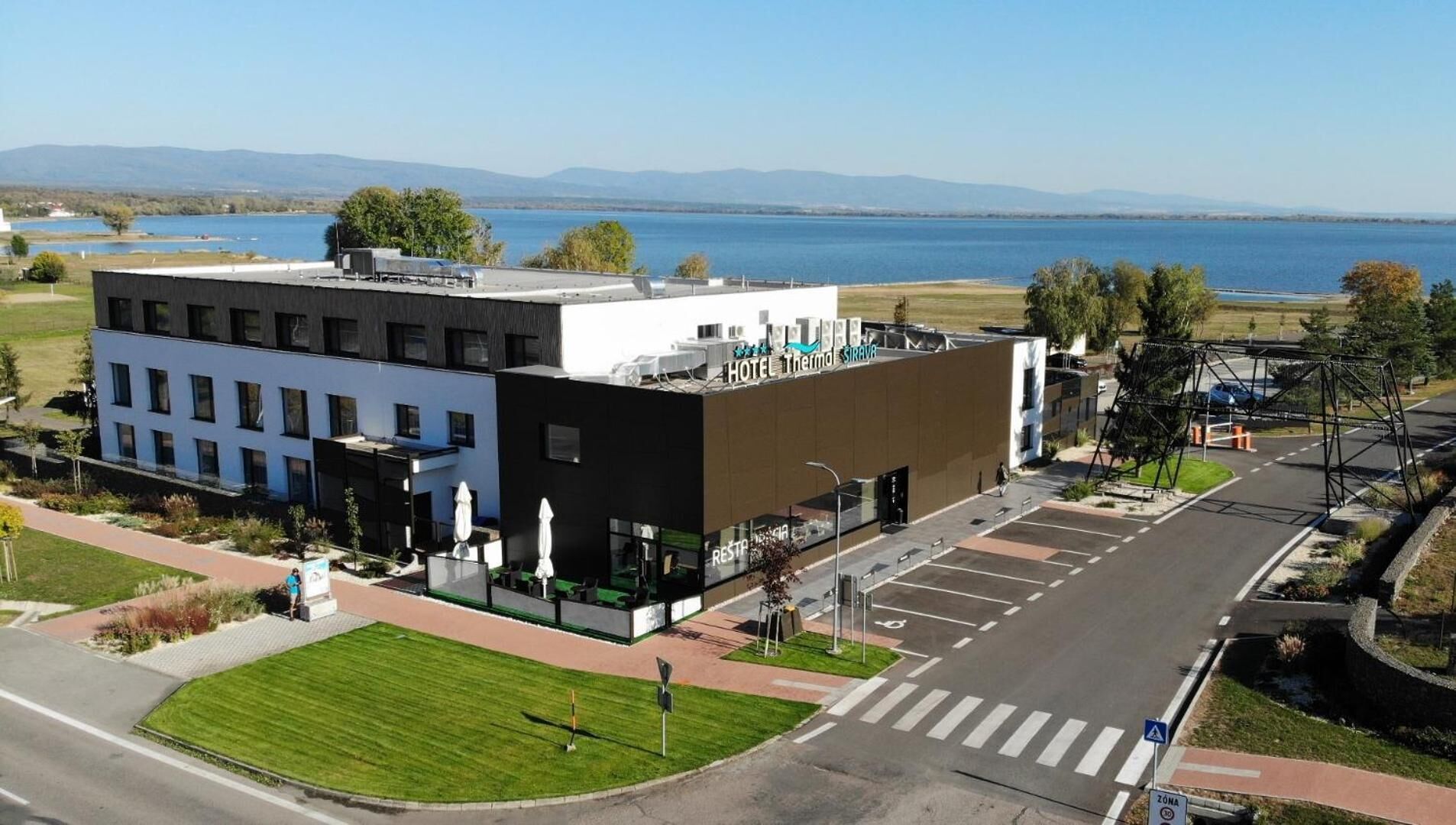 A modern hotel with a flat roof, a restaurant, and a view of a lake.