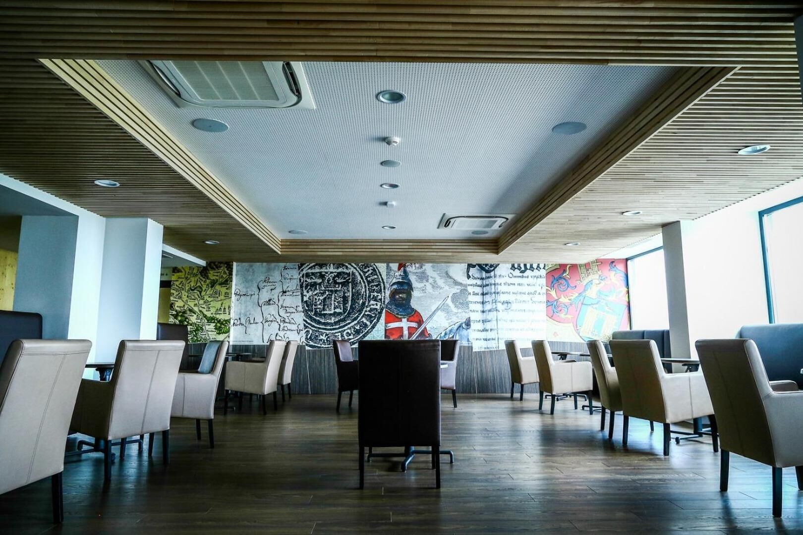 A modern interior with a high ceiling, patterned ceiling, and a mural on the back wall.
