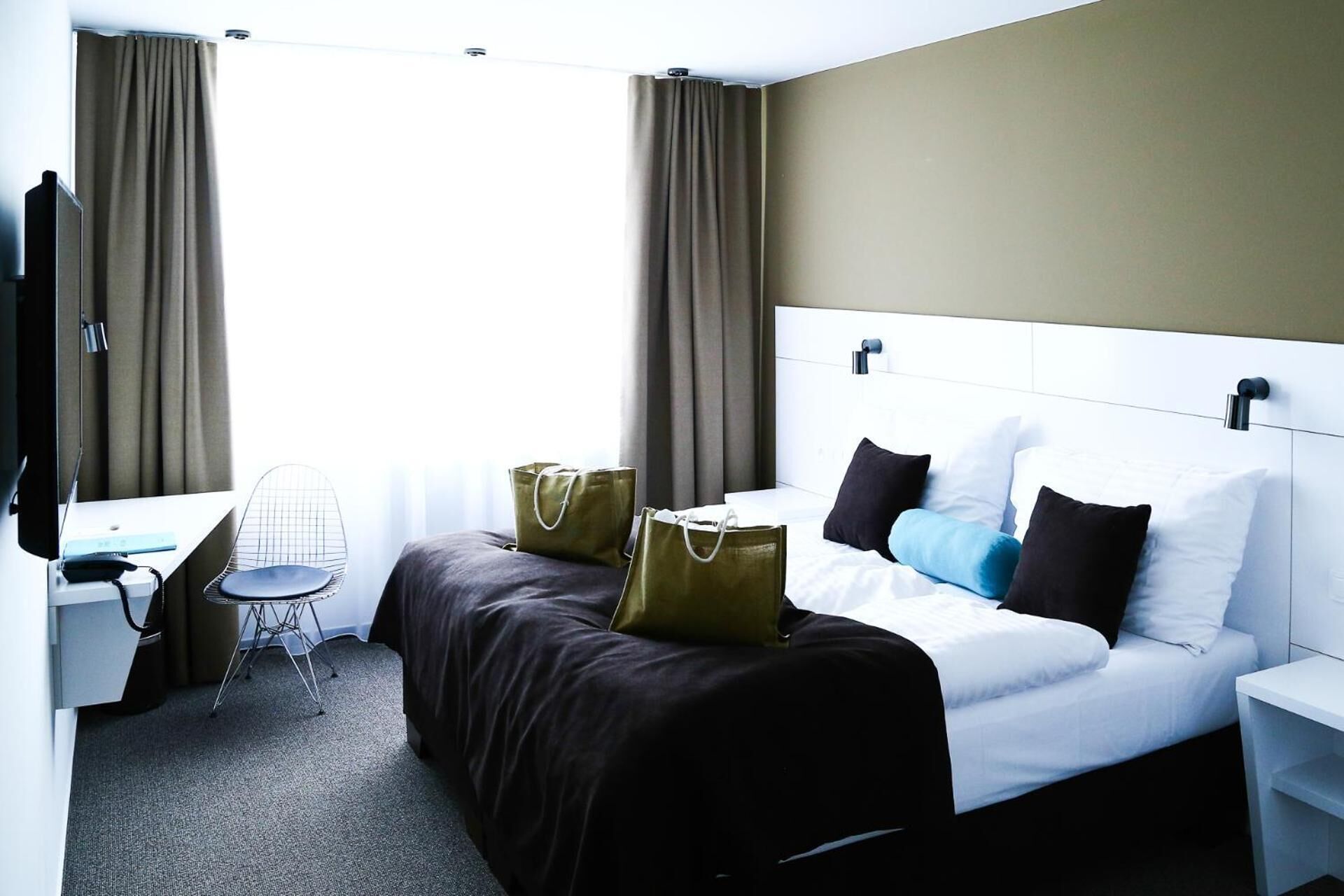 Una habitación de hotel con cama, mesita de noche, silla, escritorio y televisor.