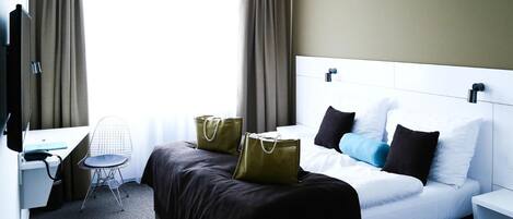 Una habitación de hotel con cama, mesita de noche, silla, escritorio y televisor.