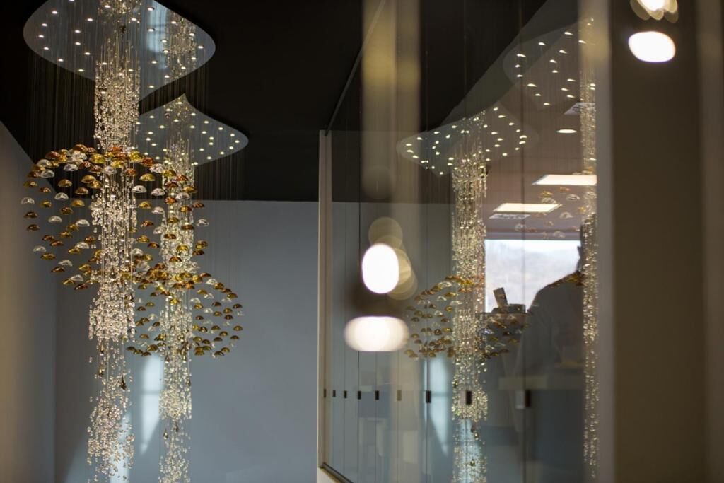 Un interior moderno con un muro de cristal reflectante y una lámpara decorativa.