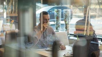 A person sitting at a table in a restaurant with a window view.