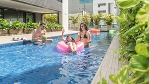 A swimming pool area with tiled flooring, potted plants, and a modern building in the background. - Porto Kaeté Hotel (Maceió)