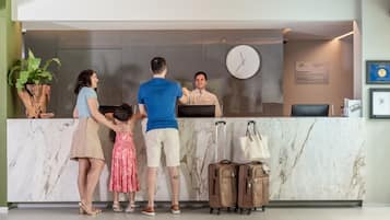 Un mostrador de recepción de hotel con un reloj, una planta y un cartel en la pared.