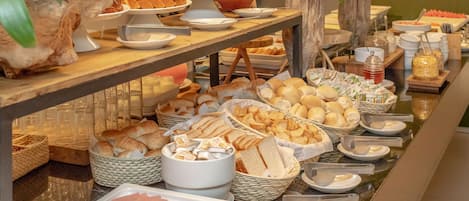 A buffet with various food items including bread, pastries, and meats.