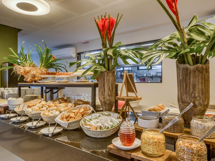 A buffet with various food items and decorative plants.
