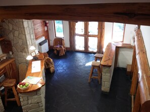 Ein rustikales Interieur mit einer Steinwand, Holzmöbeln und einem schwarzen Boden.