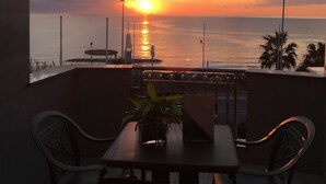 A terrace with a table and chairs, overlooking a sunset over the sea. - Serpa Hotel Anzio (Anzio)