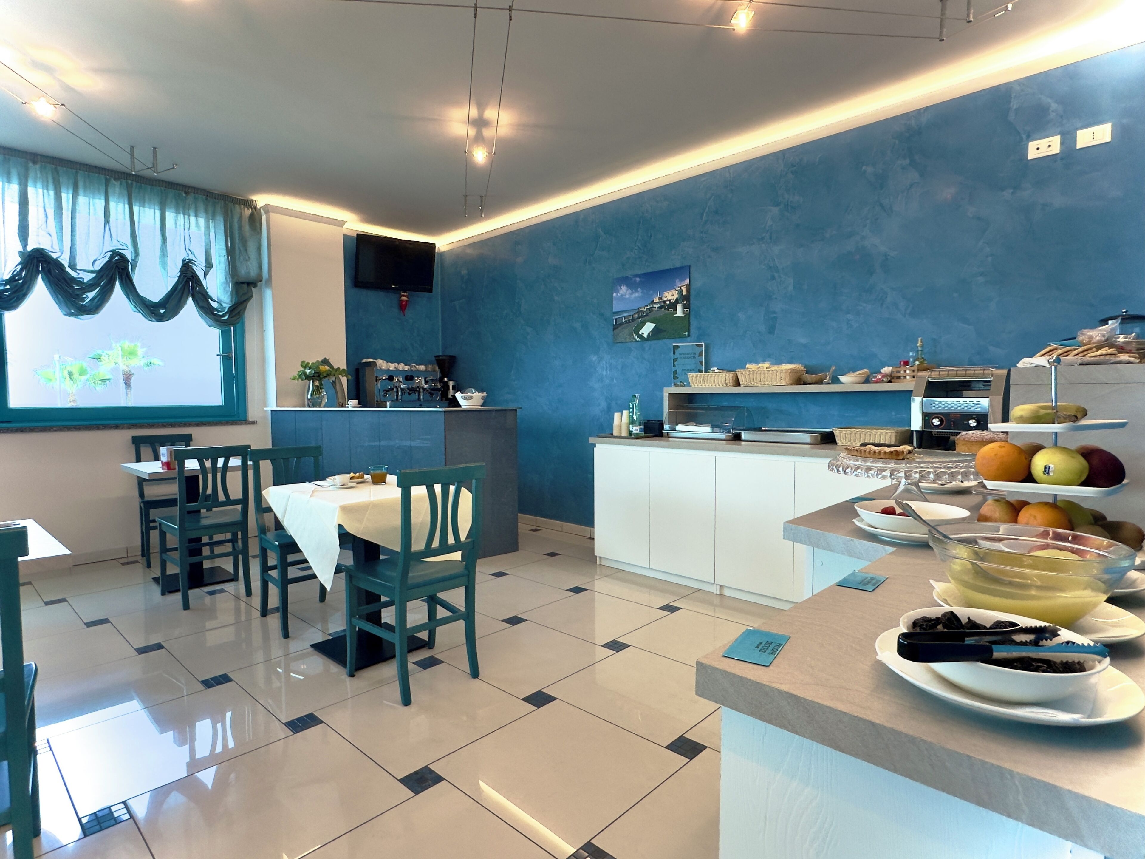A dining area with a buffet setup, a coffee machine, and a window with curtains.