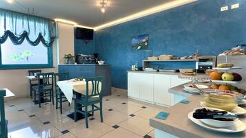 A dining area with a buffet setup, a coffee machine, and a window with curtains.