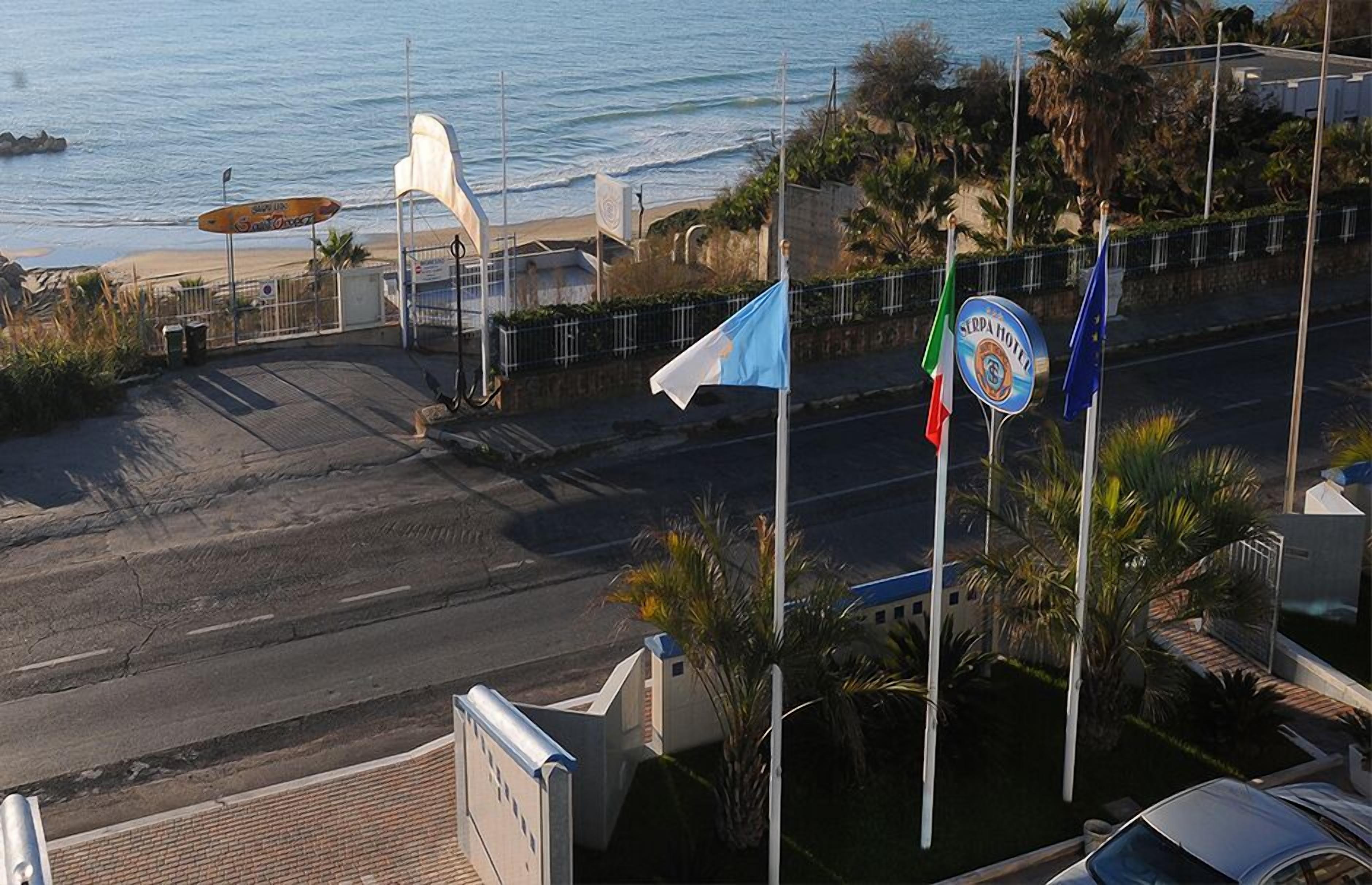Una carretera costera con banderas, una playa y un letrero de hotel.