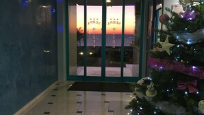 A hotel lobby with a Christmas tree, a glass door entrance, and a patterned floor. - Serpa Hotel Anzio (Anzio)