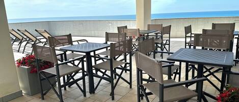 An outdoor seating area with tables and chairs, overlooking a body of water.