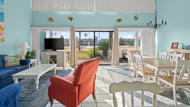 A spacious living room with a large TV, a dining area, and a view of the outdoors.