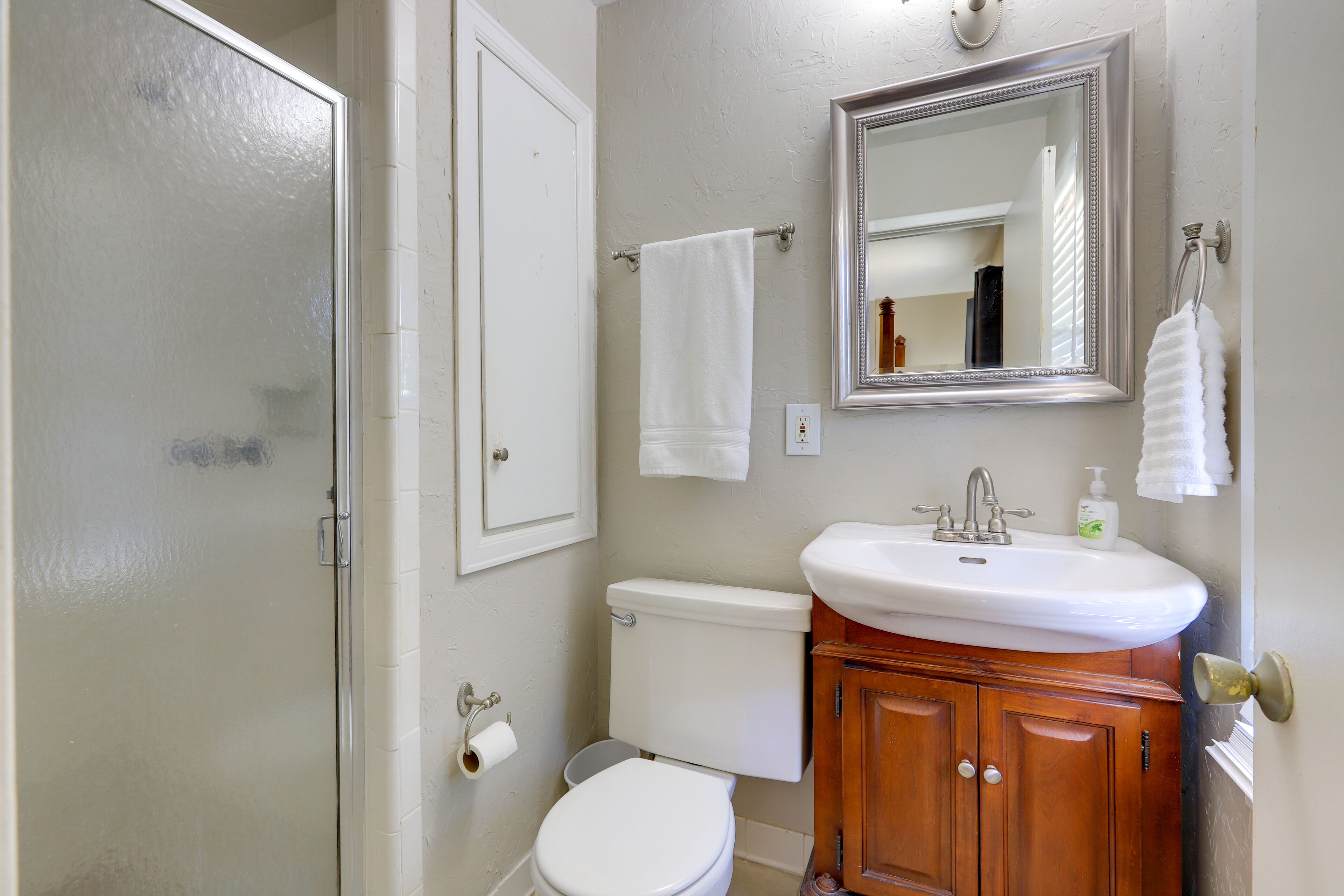 A bathroom with a toilet, sink, mirror, and towel rack.