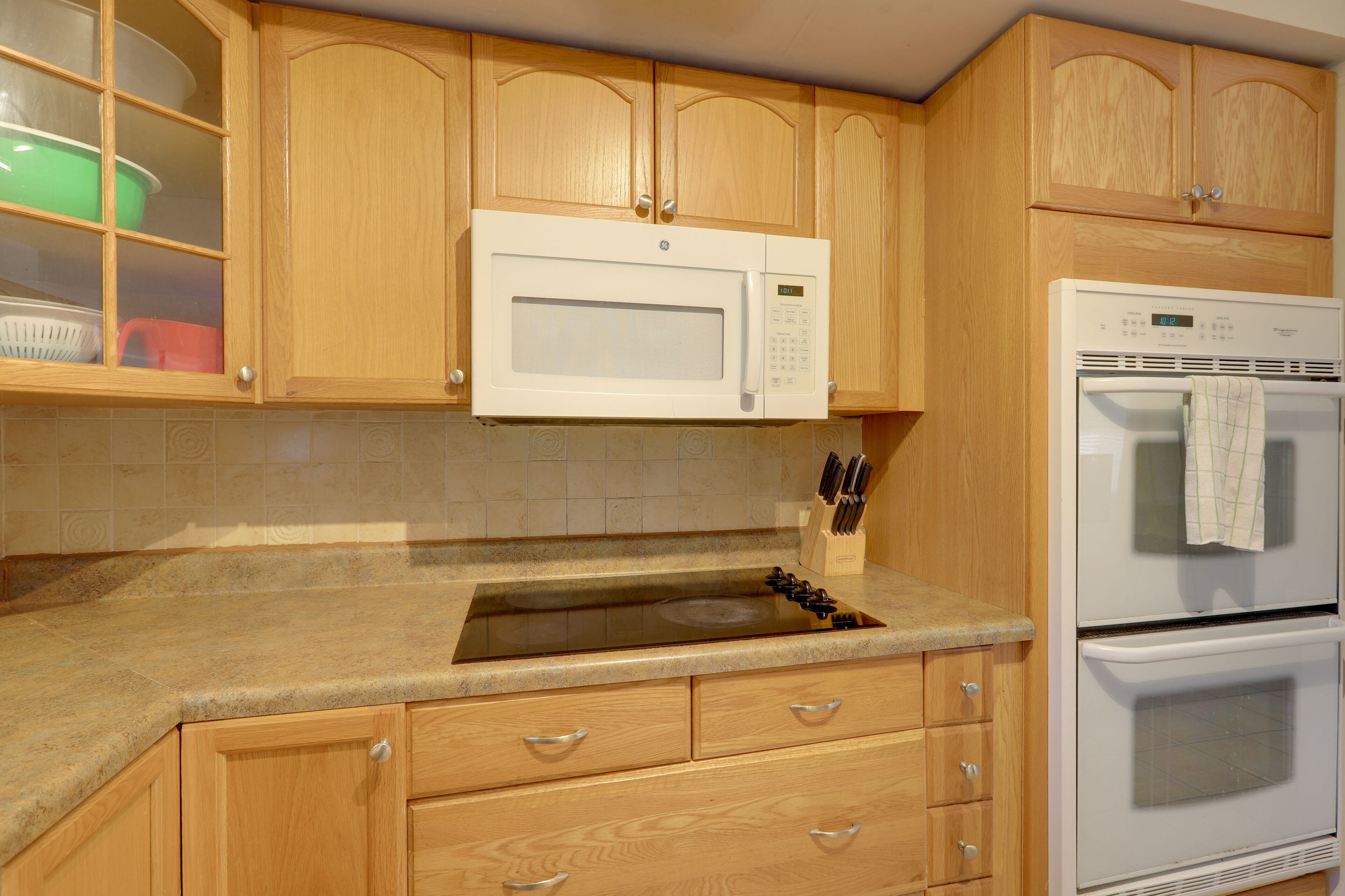 A kitchen with wooden cabinets, a built-in microwave, a stove, and a sink.