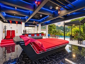 A modern bedroom with a large bed, a pool area, and a view of the outdoors.