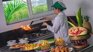 A chef cooking on a stove with a window view of greenery. - Private pool villa Nap Dau Crown for Family and Friends/ Private Chef available (ต.ฉลอง)