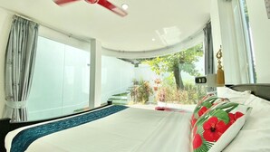 A modern hotel room with a large bed, a ceiling fan, and a view of a garden and staircase. - Private pool villa Nap Dau Crown for Family and Friends/ Private Chef available (ต.ฉลอง)