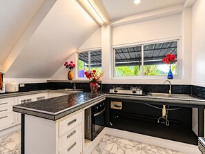 Cozinha moderna com esquema de cores preto e branco, forno embutido e janela com vista para área verde.