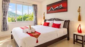 A hotel room with a large bed, a ceiling fan, a painting, and a view of greenery outside. - Villa Nap Dau Crown Private pool villa for Family and Friends (ต.ฉลอง)