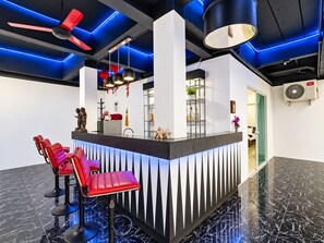 A reception area with a counter, red chairs, and a ceiling fan. - Villa Nap Dau Crown Private pool villa for Family and Friends (ต.ฉลอง)
