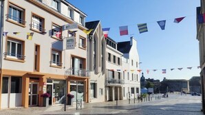 Un hotel con letrero que indica que lo es, un balcón y una calle empedrada.