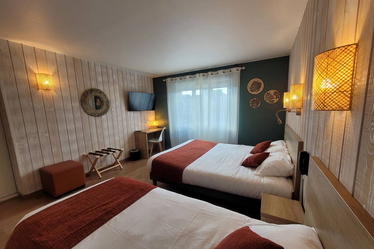 A hotel room with two beds, a desk, a chair, a TV, and a window with curtains.