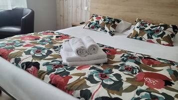 Una cama bien hecha con ropa de cama floral, un cabecero de madera y una silla en una habitación con paneles de madera.
