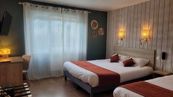 Habitación de hotel con dos camas, un escritorio y una silla. Cuenta con luces empotradas y un televisor de pantalla plana.