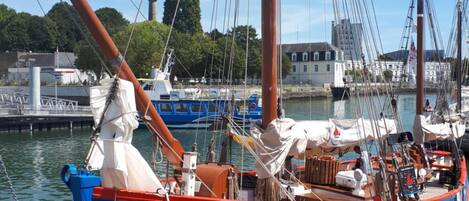 A blue and red boat named "Andre Sette" docked at a marina with a clear sky and buildings in the background.