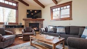 A cozy living room with a fireplace, leather sofas, a coffee table, and a flat-screen TV. - Private Home with Hot Tub! Mountain Views! Short walk to Village! (Mammoth Lakes)
