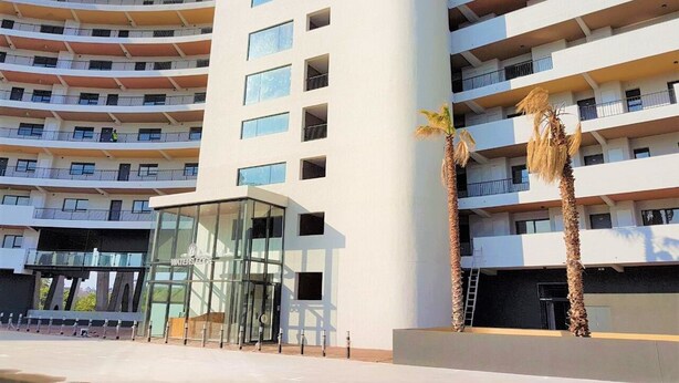 A multi-story hotel with a modern design, featuring a central glass entrance and multiple balconies. - Waters Edge 615 by CTHA (Cape Town)