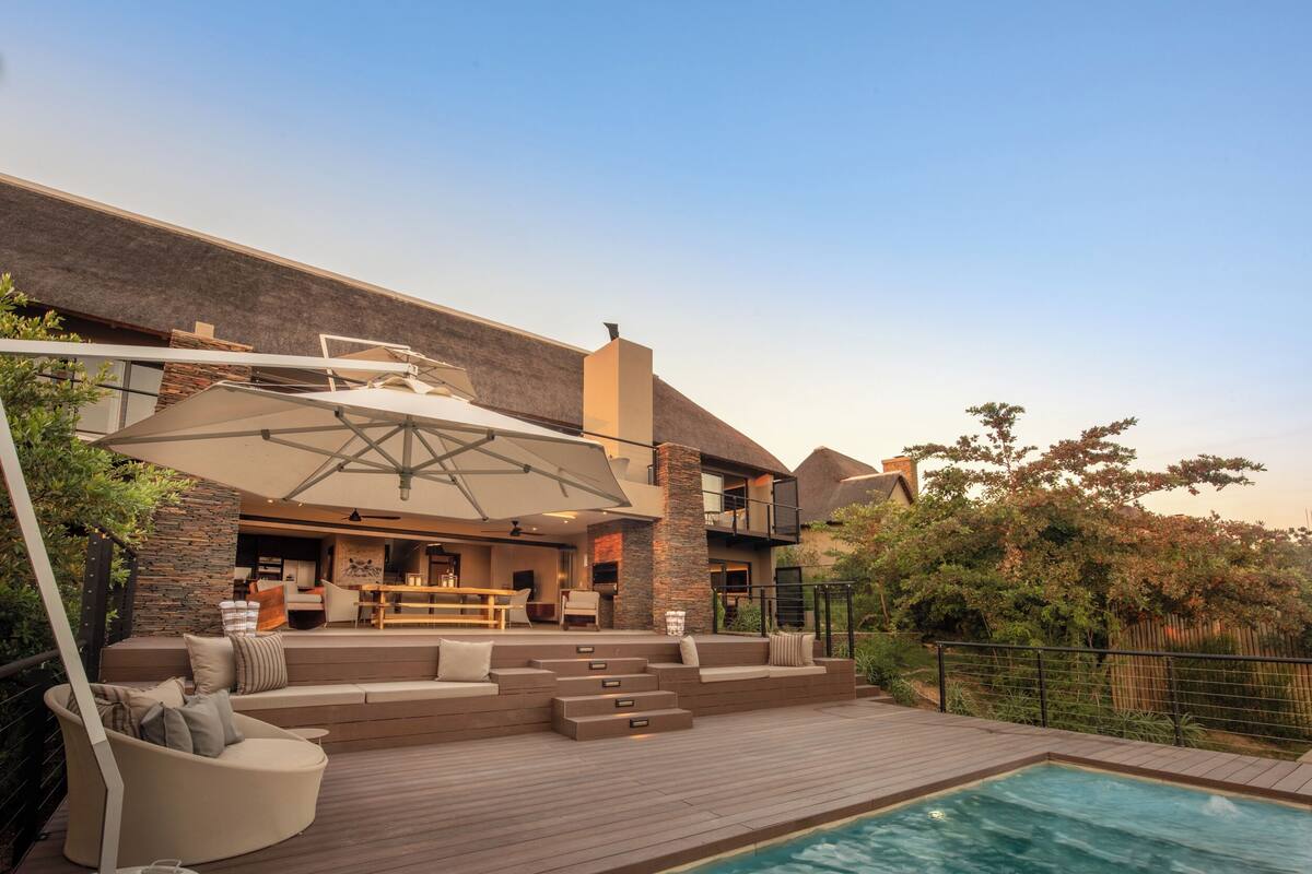 A modern outdoor living area with a pool, seating, and a bar.
