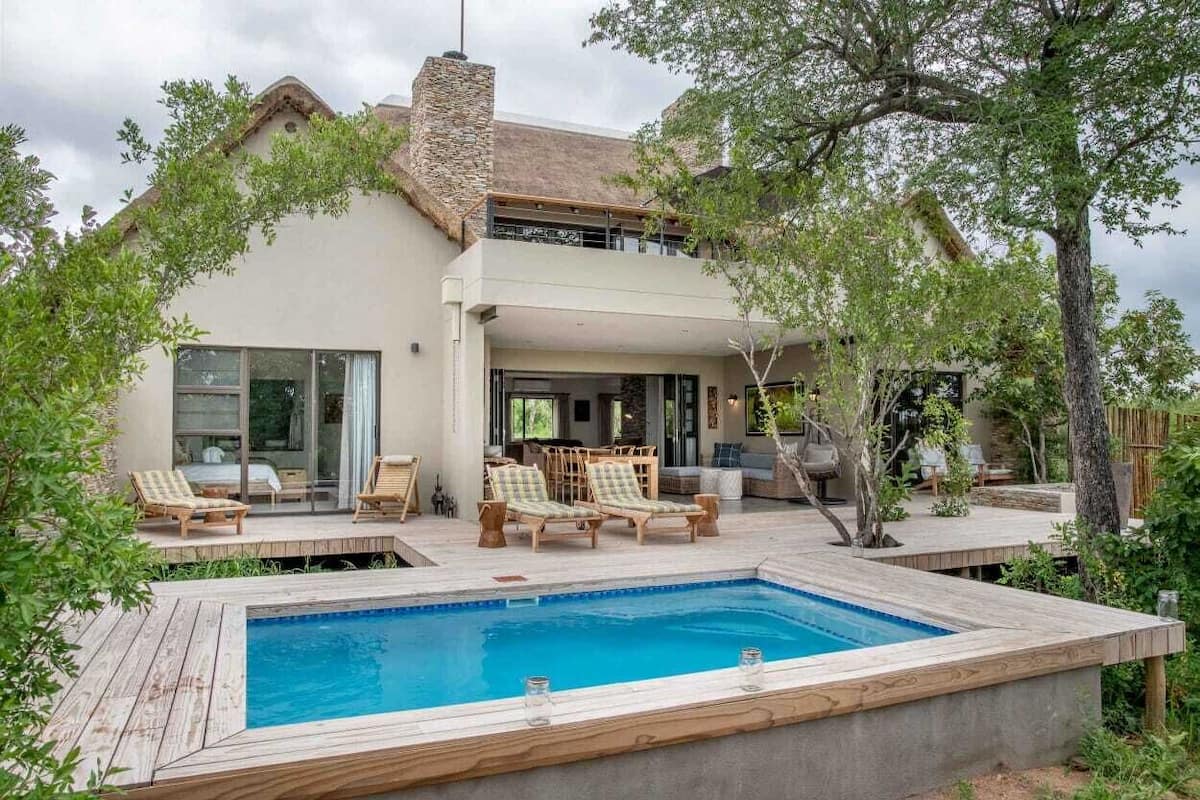 A modern house with a swimming pool, outdoor seating, and a covered patio area.