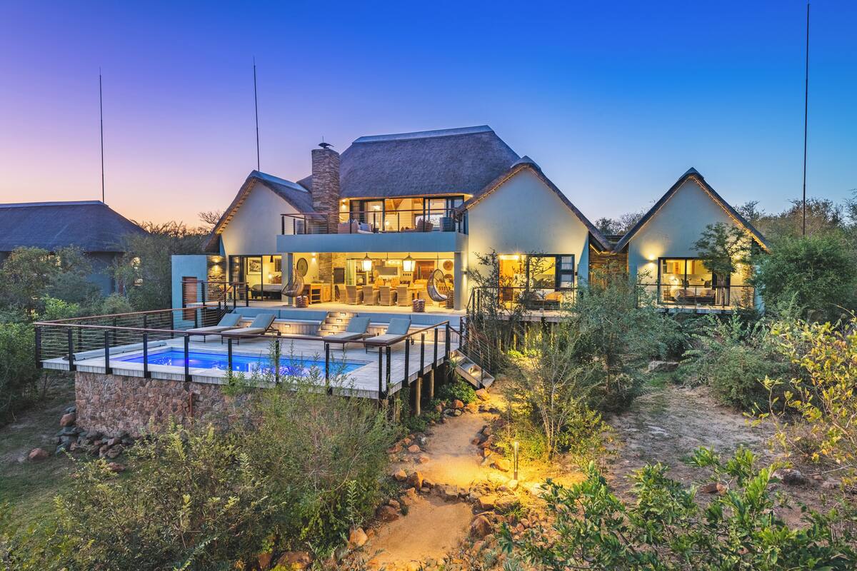 A modern house with a swimming pool, outdoor seating, and a stone pathway.