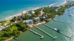 An aerial view of a coastal area with a beach, houses, and a pier. - Aquarius North:  7BR/5BA luxury beach house w/ heated pool + spa,  dock & more!  (Stuart)