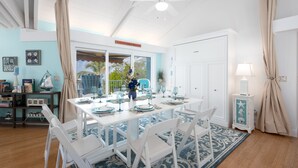 A dining area with a white table set for four, surrounded by white chairs, a ceiling fan, and a view of the outdoors. - Aquarius North:  7BR/5BA luxury beach house w/ heated pool + spa,  dock & more!  (Stuart)