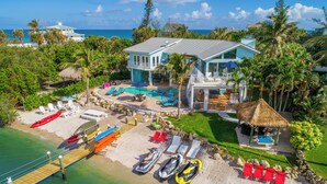 A resort with a pool, beach chairs, and a thatched-roof hut. - Aquarius North:  7BR/5BA luxury beach house w/ heated pool + spa,  dock & more!  (Stuart)