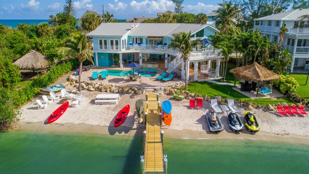 A beachfront property with a pool, lounge chairs, and a dock. - Aquarius North:  7BR/5BA luxury beach house w/ heated pool + spa,  dock & more!  (Stuart)