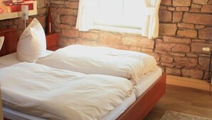 A double bed with white linens in a room with stone walls and a wooden floor. - Hotel Gasthaus Gellenberg (Rehlingen-Siersburg)