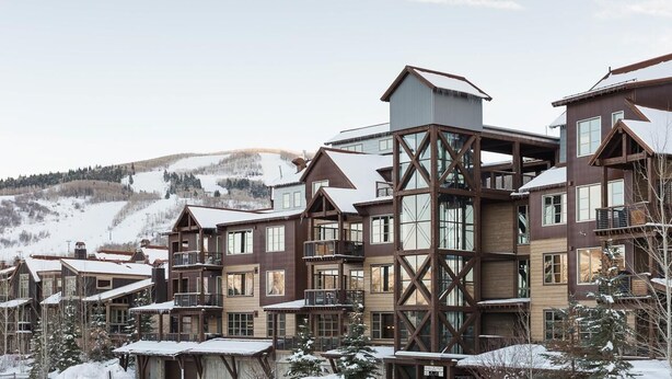 A multi-story hotel with a wooden exterior and large windows, set in a snowy mountainous area.