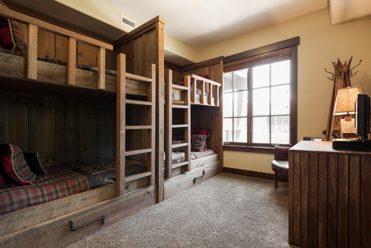 A cozy room with a loft bed, built-in shelves, a desk, and a window.