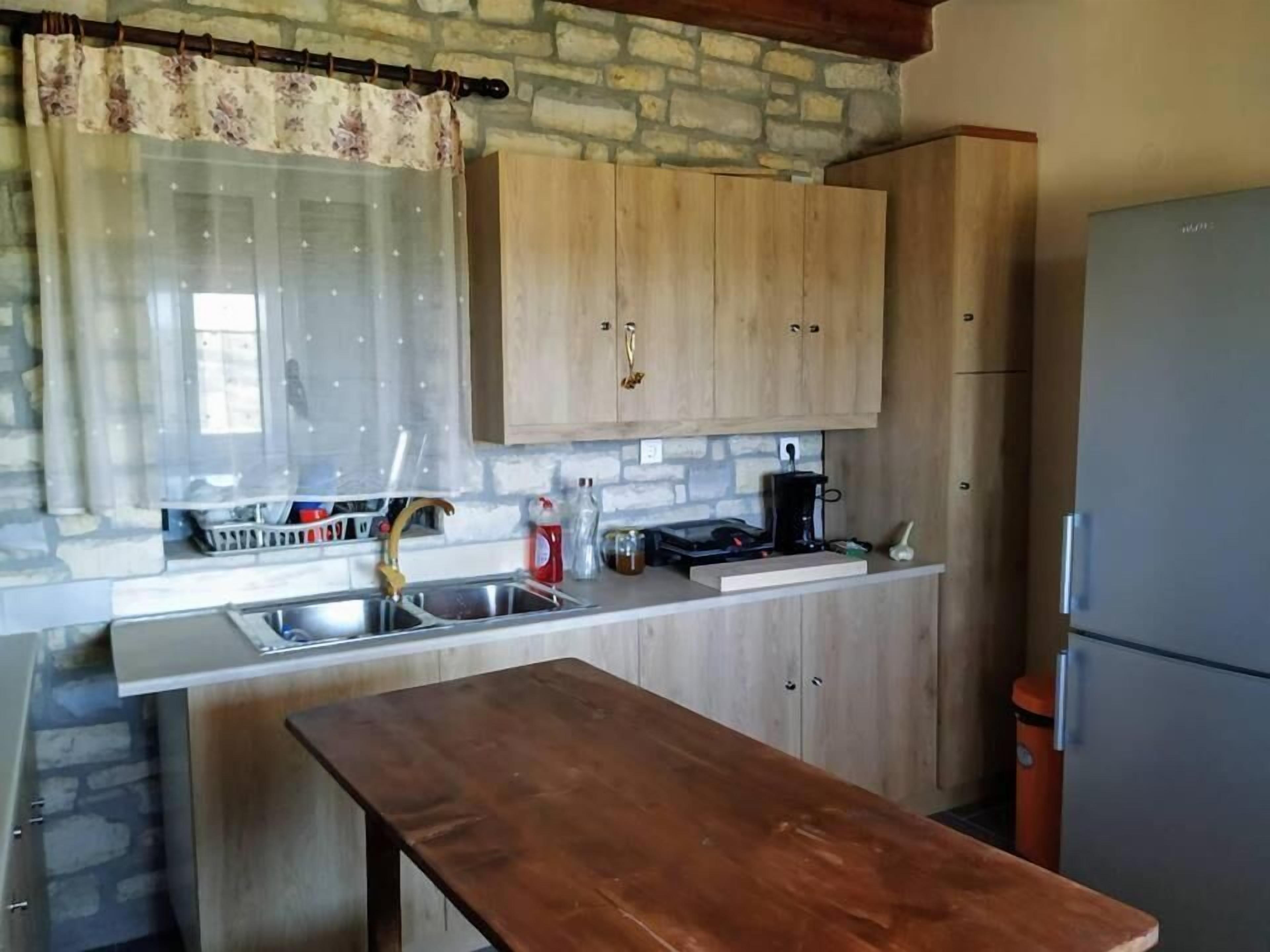 A kitchen with wooden cabinets, a stainless steel sink, a coffee maker, and a refrigerator.