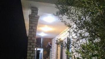 An outdoor area with a stone pillar, a metal railing, and a staircase leading to a balcony.