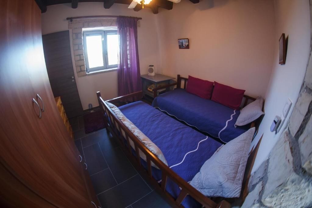 Un dormitorio con dos camas, una ventana con cortinas, una mesita y un armario.