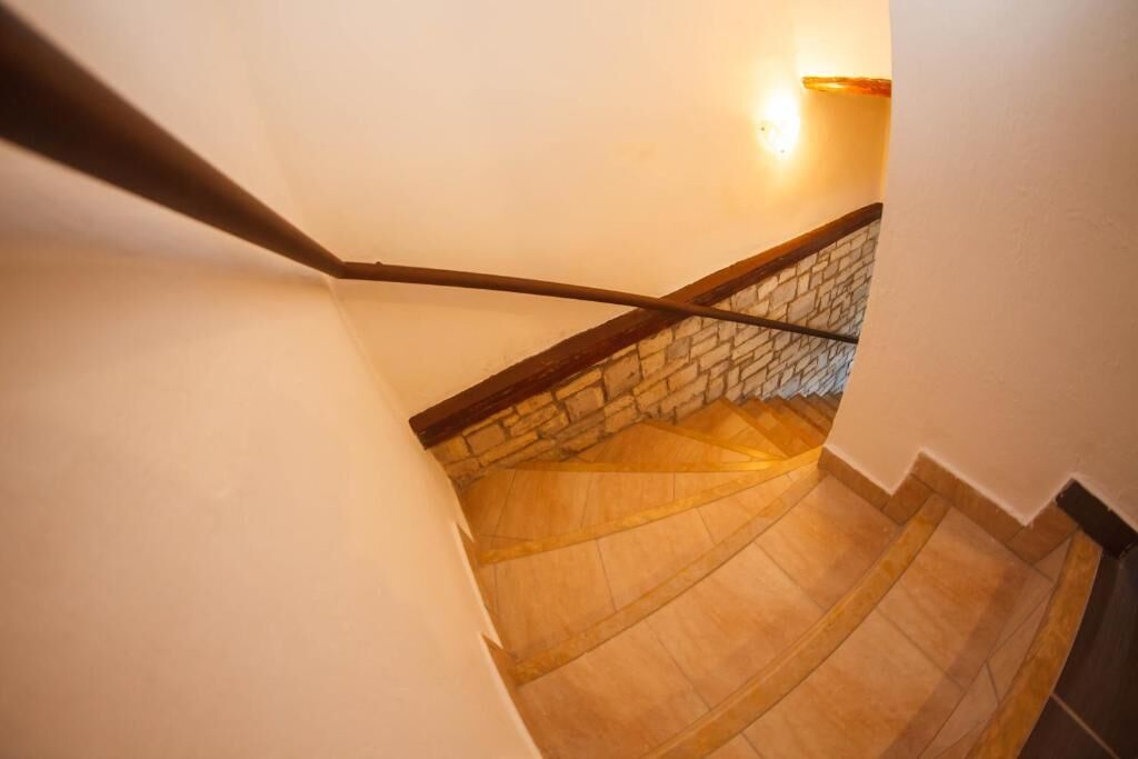 Un escalier avec une rampe en bois et un mur en pierre à sa base.