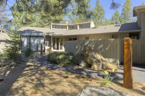 Surrounded by lush vegetation and a natural rock formation, this two-story house offers a serene retreat.